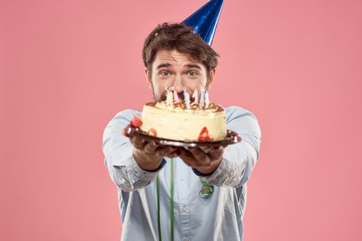 Bearded man with cake tongue on a pink background cropped view and a blue cap on his head. High quality photo