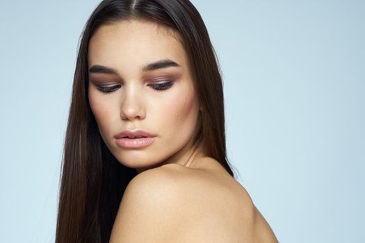 Pretty brunette with bared shoulders long hair body care blue background. High quality photo