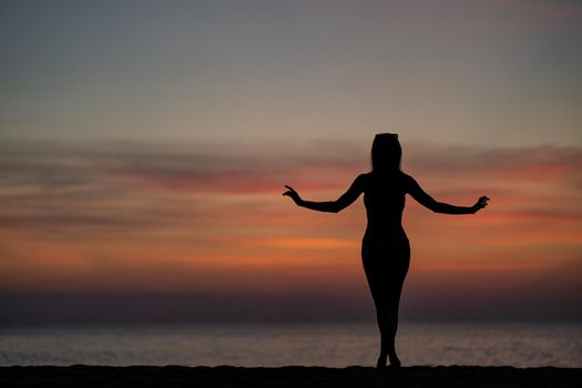 Silhouette portrait of woman wearing bikini on the beach, golden sunset moment. Holiday and travelling concept.