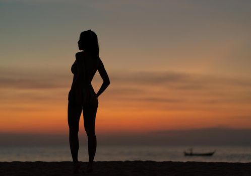 Silhouette portrait of woman wearing bikini on the beach, golden sunset moment. Holiday and travelling concept.