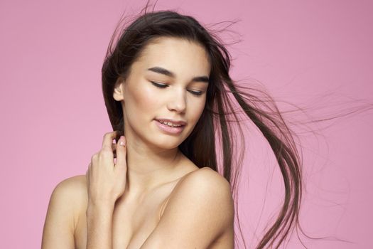 Pretty brunette naked shoulders clear skin pink background. High quality photo
