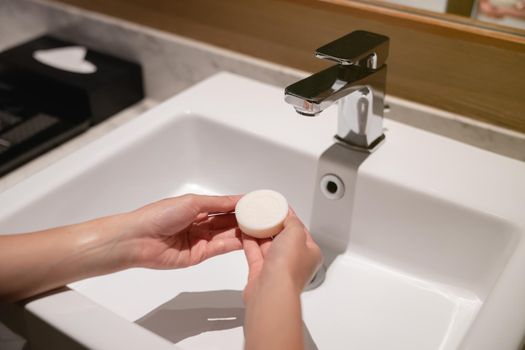 Woman wash hands with soap in the sink with water.