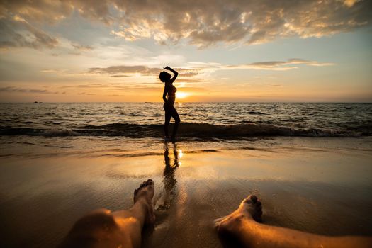 woman silhouette on the beach at sunset with man Legs