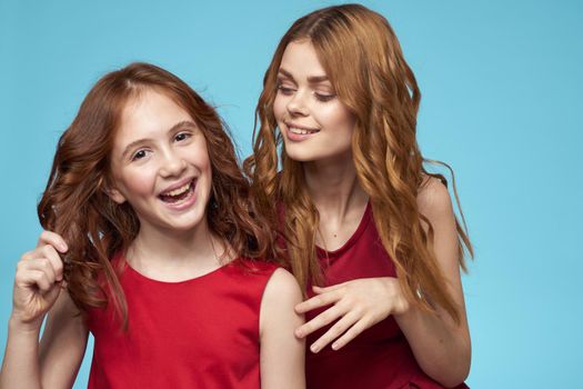 Family mom and daughter hug red dresses communication emotions blue background. High quality photo