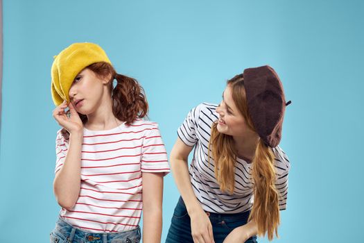 Fashion sisters in hats fun lifestyle blue background studio. High quality photo