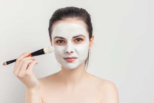 woman with bare shoulders as face mask brush for applying. High quality photo