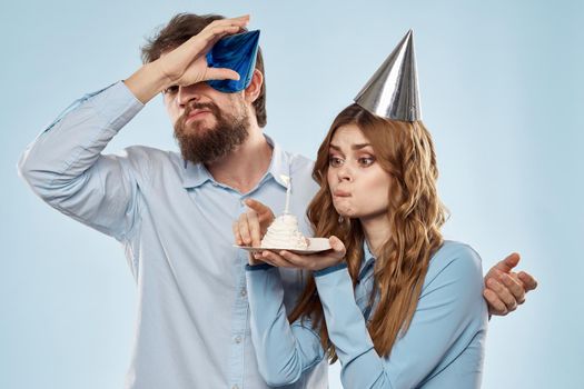 Cheerful man and woman with cake in a plate corporate party blue background. High quality photo