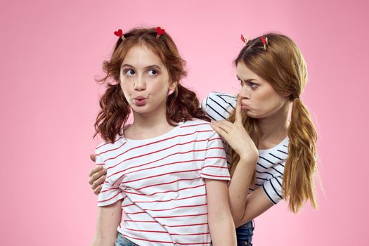 cheerful girl and woman on a pink background sisters family emotions. High quality photo