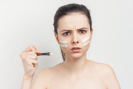 bare-shouldered brunette applying makeup on face cropped view. High quality photo