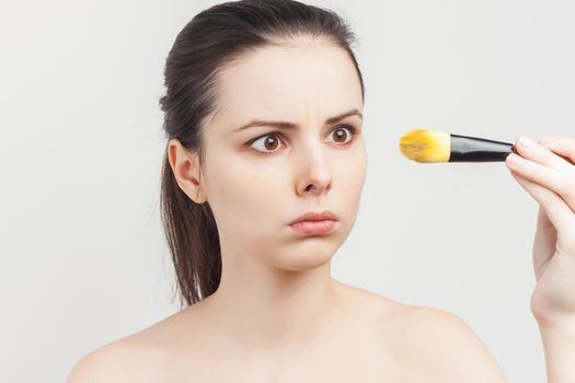 bare-shouldered brunette applying makeup on face cropped view. High quality photo