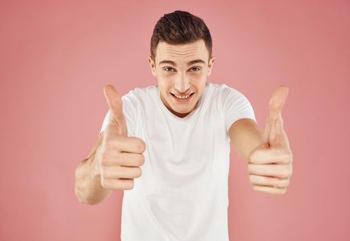 Guy on a pink background gesturing with his hands in a white t-shirt cropped view. High quality photo
