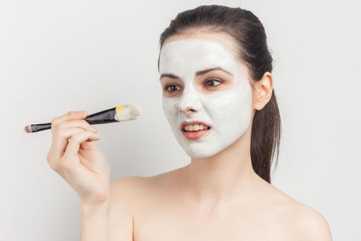 woman with bare shoulders with a brush in her hands applying makeup. High quality photo