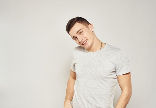 Cheerful handsome man in a white T-shirt gray background. High quality photo