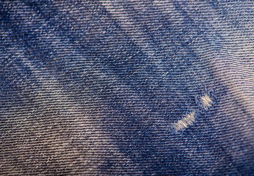 Texture of blue jeans background, ripped jeans.