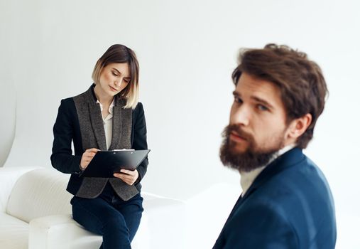Business woman In a bright room and an upset man with a beard in the foreground is job interview. High quality photo