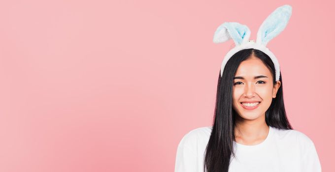 Happy Easter Day. Beautiful young woman smiling wearing rabbit ears, Portrait female happy face standing looking at camera, studio shot isolated on pink background