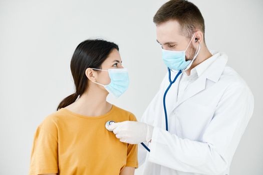 doctor in a medical gown examines a female patient in a blue mask. High quality photo