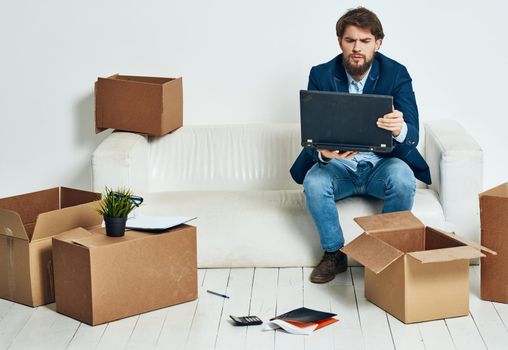 Man sitting on sofa with laptop office boxes with things work. High quality photo
