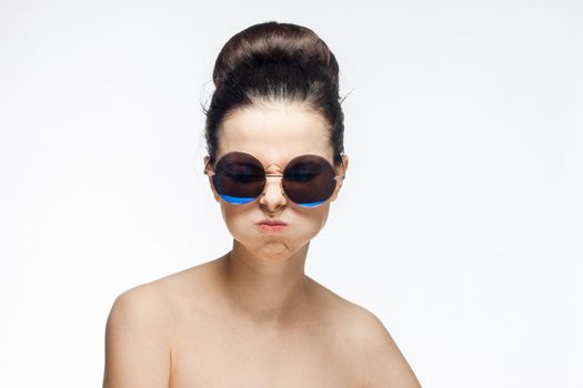 pretty woman naked shoulders and sunglasses light background fashion. High quality photo