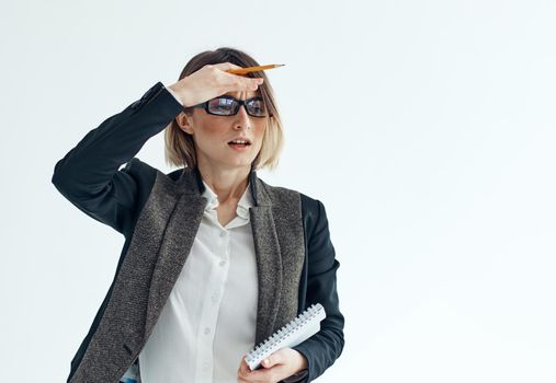 A woman with a notebook and a pen in her hands on a light background business finance suit. High quality photo