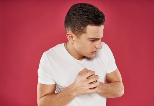 Man with displeased facial expression emotions white t-shirt studio red background. High quality photo