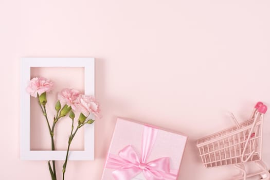 Concept of Mother's day holiday greeting design with carnation bouquet and gift on pink background