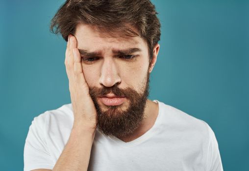 Upset man with a beard touches his head with his hands on a blue background. High quality photo