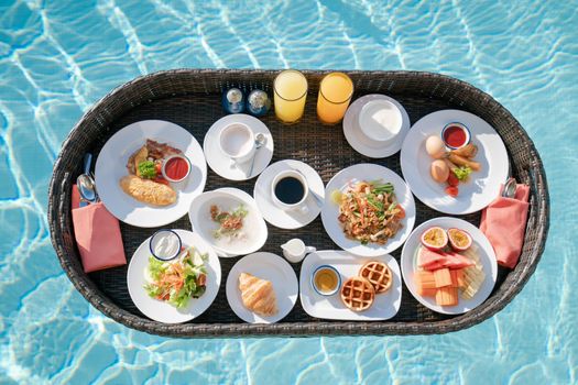 Breakfast in swimming pool, floating breakfast set in tray in resort.