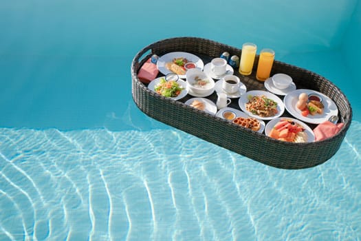 Breakfast in swimming pool, floating breakfast set in tray in resort.