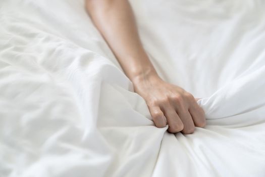 Women hand pulling or grasping white sheets. Hand sign orgasm of woman on white bed sheet.