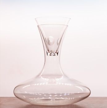 Transparent pitcher with glass on wood table with white background.