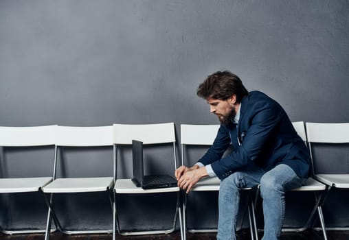 Business man in a suit sits on a chair in front of a laptop work lifestyle. High quality photo