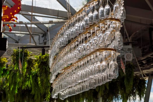 Several rows of champagne glasses hang on a chandelier-shaped counter. Decorative modern chandelier.