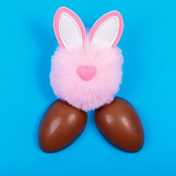 Easter, chocolate egg, pink toy rabbit head on a blue background. Place for text