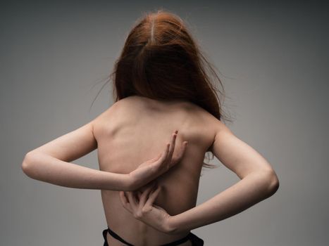 nude woman gesturing with her hands red hair light background. High quality photo