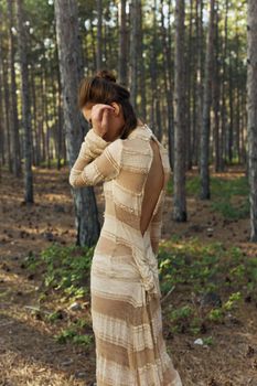 Back view of romantic woman in dress in forest holds hand near face. High quality photo