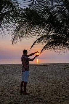 sunrise on the beach with palm trees, Chumphon Thailand,men watching sunset on the beach in Thailand Asia