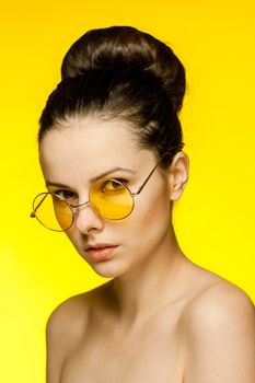 brunette with bare shoulders yellow glasses clear skin model. High quality photo