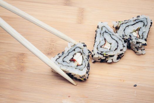 triangular sushi rolls chopsticks wooden background asian cuisine. High quality photo