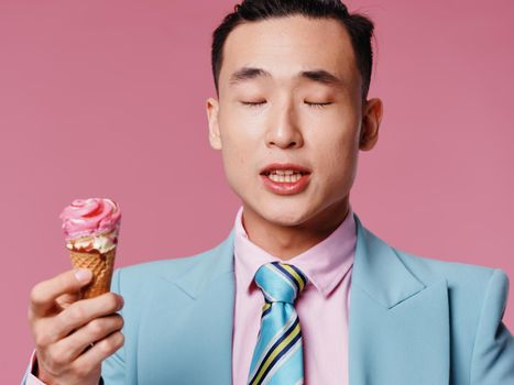 A man holds a cone with ice cream in his hand. Asian appearance blue jacket tie. High quality photo
