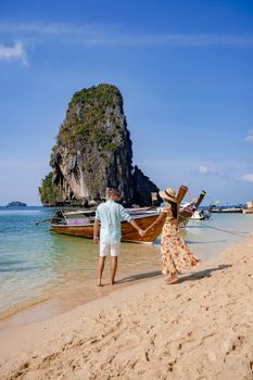 couple mid age on a tropical beach in Thailand, tourist on a white tropical beach, Railay beach with on the background longtail boat. Railay Beach in Krabi province. Ao Nang, Thailand.