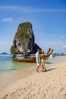couple mid age on a tropical beach in Thailand, tourist on a white tropical beach, Railay beach with on the background longtail boat. Railay Beach in Krabi province. Ao Nang, Thailand.