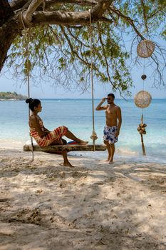 A couple from behind on the backside looking out over the ocean of tropical Island, men and woman vacation, beautiful tropical island beach Koh Kham, Trat Thailand couple relax on tropical Island. 