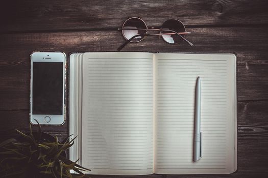 open notepad lies on a wooden table and pen glasses mobile phone. High quality photo