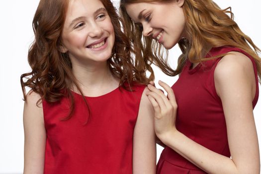 Cheerful mom and daughter in red dresses socializing light background. High quality photo