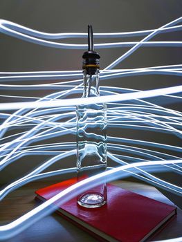 Small narrow bottle with bartender pourer on table with light paiting around