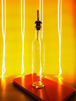 Small narrow bottle with bartender pourer on table with light paiting around