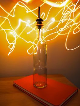 Small narrow bottle with bartender pourer on table with light paiting around