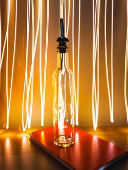 Small narrow bottle with bartender pourer on table with light paiting around