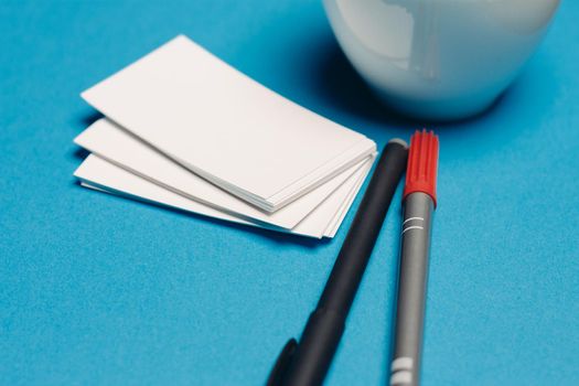 business cards on blue background and pen coffee cup top view. High quality photo